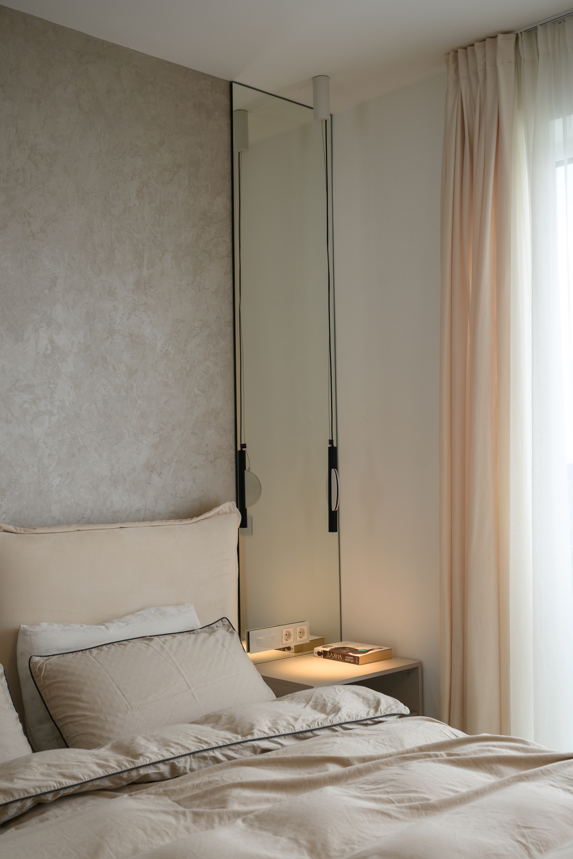 Beige bedroom with a mirror, pendant lighting and soft curtains